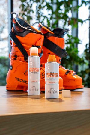 Two DFNS Sportswear Refresher bottles standing before a pair of orange ski boots.
